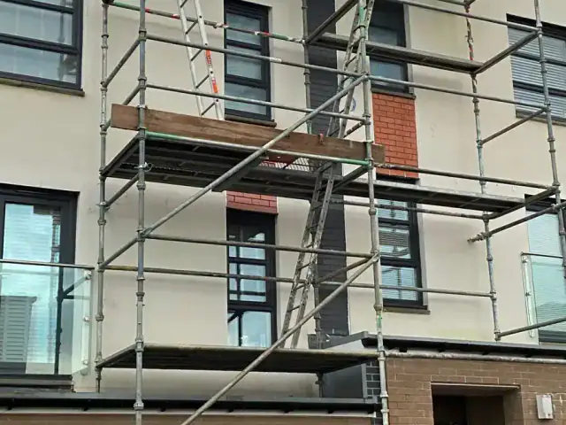 Scaffolding erected against a modern three-storey townhouse