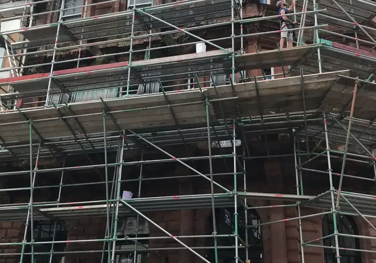 Scaffolding around the upper floors of a red sandstone tenement