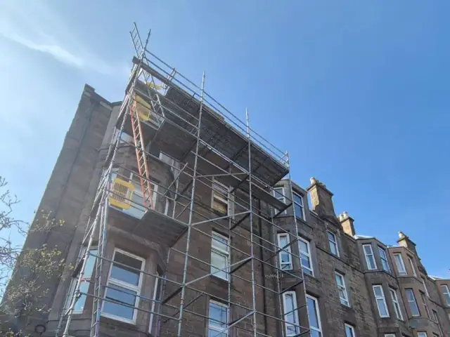 Scaffolding the full height of a sandstone tenement, up to roof level